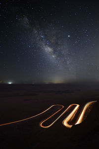 Light trails on road against sky at night