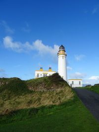 Lighthouse by building against sky