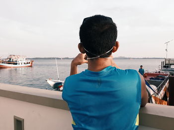 Rear view of man standing by sea against sky