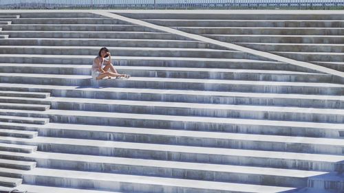 Woman using mobile phone on staircase