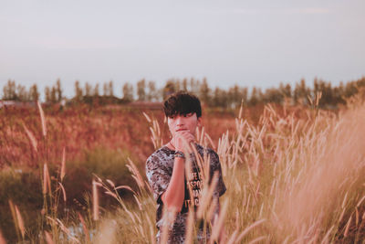 Man looking away while standing by plants against sky