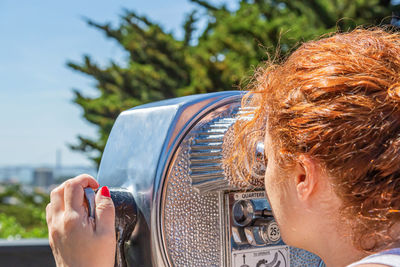 Woman tourist looking into the distance through coin operated binoculars.