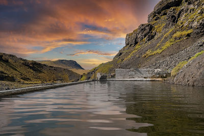 Beautiful seljavallalaug geothermal hotspring pool by mountain during sunset