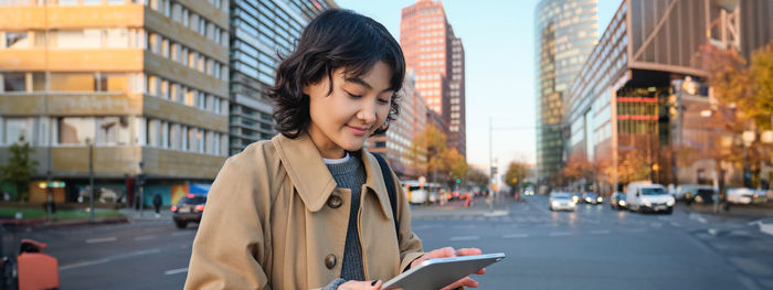 Young woman looking away while standing in city