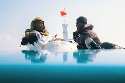 People sitting in swimming pool against sky