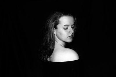 Close-up of young woman over black background