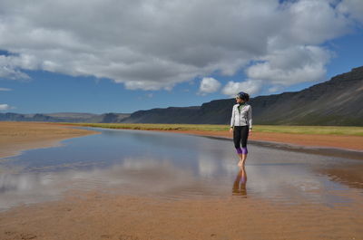 Woman walking on shore against sky