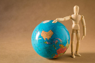 Close up of figurine standing by globe on table