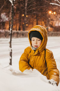 Portrait of smiling boy standing on snow covered field