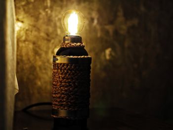 Close-up of illuminated light bulb on table against wall