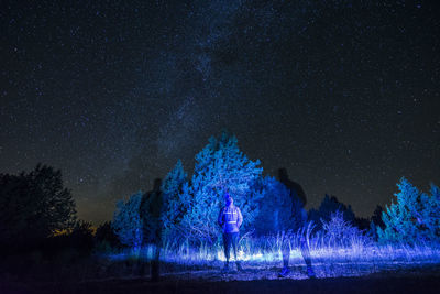 Illuminated light painting on field against sky at night