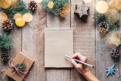 Christmas background with fir tree branches, pine cones, and hand writing in notepad