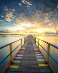 Bridge over calm sea against sky during sunset