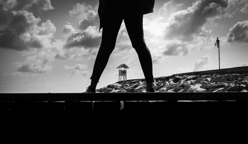 Low section of silhouette person standing against sky