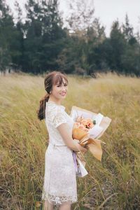 Portrait of smiling bride holding bouquet while standing