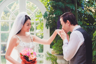 Married couple holding bouquet sitting outdoors