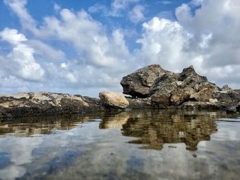 Reflection of rocks in sea against sky