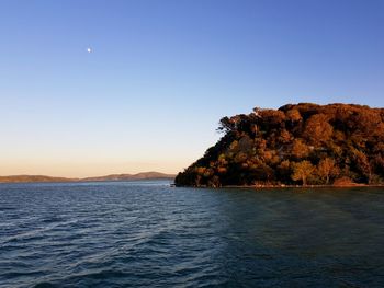 Scenic view of sea and mountains against clear blue sky