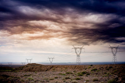 Wind turbines on field against cloudy sky