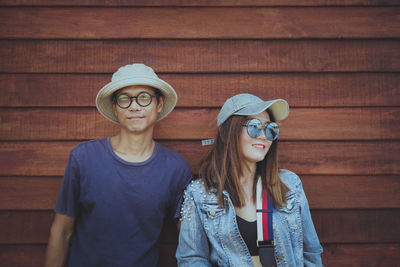 Asian couples wearing clothes hat and casual lifestyle standing against wooden wall