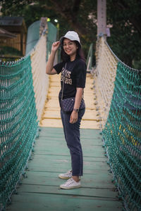 Portrait of young woman standing on footbridge