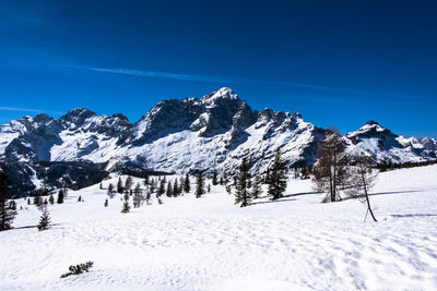 Scenic view of snow covered mountains against blue sky