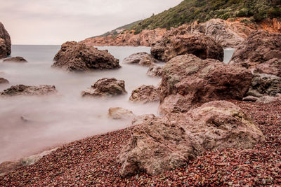 Scenic view of rocks in sea against sky