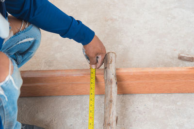 Low section of worker measuring wood
