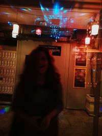 Portrait of smiling woman standing against illuminated lights