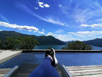 Low section of person by swimming pool against sky