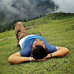 Rear view of man sitting on field against sky