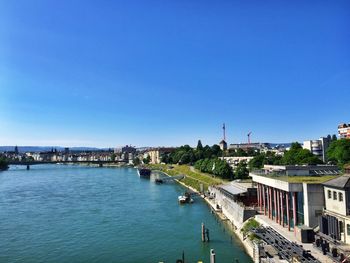 River amidst buildings against clear blue sky