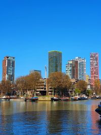 River by modern buildings against clear blue sky