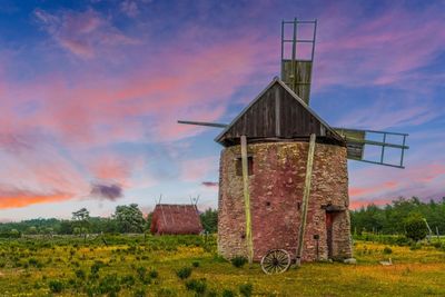 Old windmill on field against sky