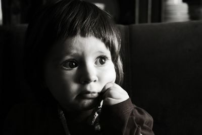 Close-up of thoughtful baby girl looking away while sitting in darkroom