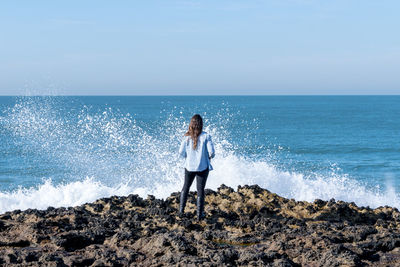 Young woman standing on beach against clear sky