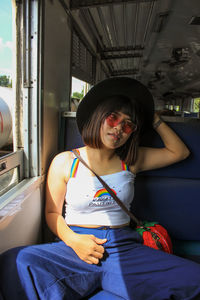Young woman wearing sunglasses sitting by window in train