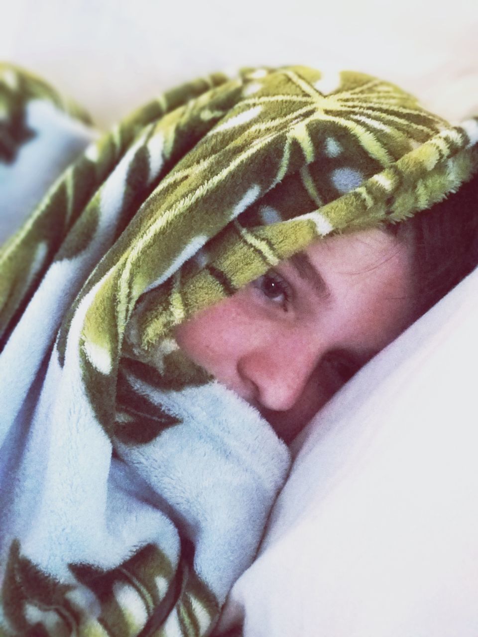 CLOSE-UP PORTRAIT OF CUTE BOY LYING ON BED