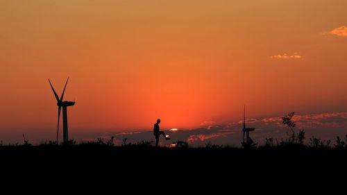 Silhouette man on field against sky during sunset