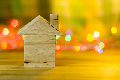 Close-up of wooden model home on table against illuminated lights