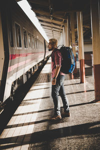 Side view full length of man standing at railroad station platform