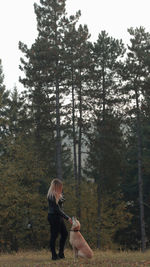 Woman with dog on street amidst trees