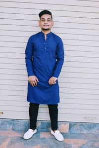 Portrait of young man standing against wall