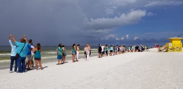 People shore at beach against sky