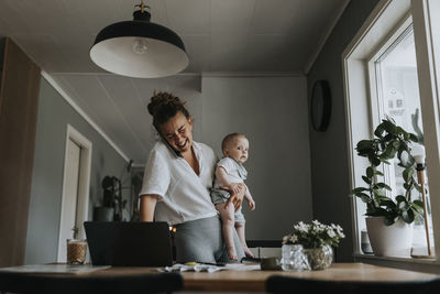 Multitasking mother taking care of baby and working from home