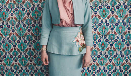 Midsection of woman wearing traditional clothing against patterned wall