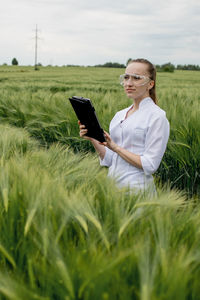 Young woman using mobile phone while standing on grassy field