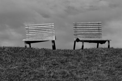 Empty bench on field against sky