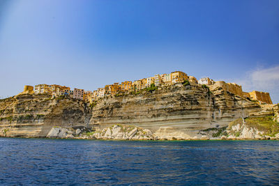 Rock formations by sea against clear blue sky