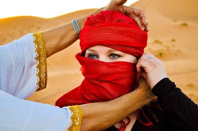 Cropped hands adjusting woman scarf on desert